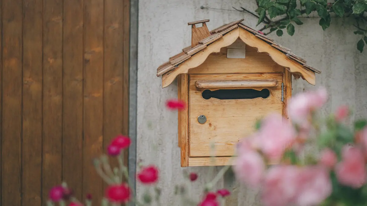 Postkasse i tre på en vegg med blomster foran